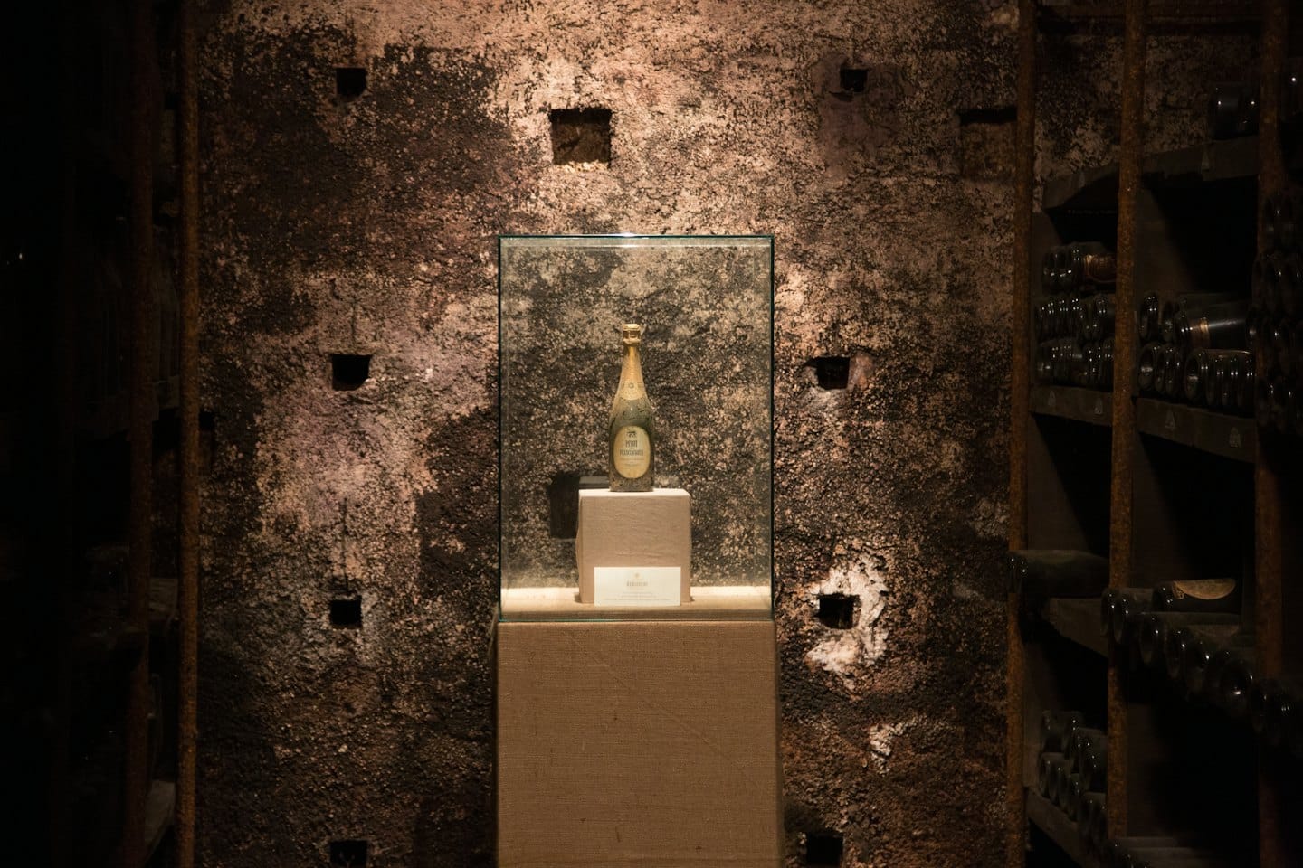 Bottiglia di champagne vintage in una teca di vetro su un piedistallo.