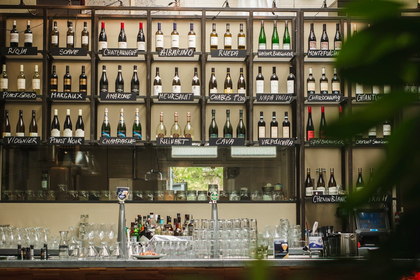 Bottiglie di vino esposte su scaffali di metallo sopra un bancone da bar.
