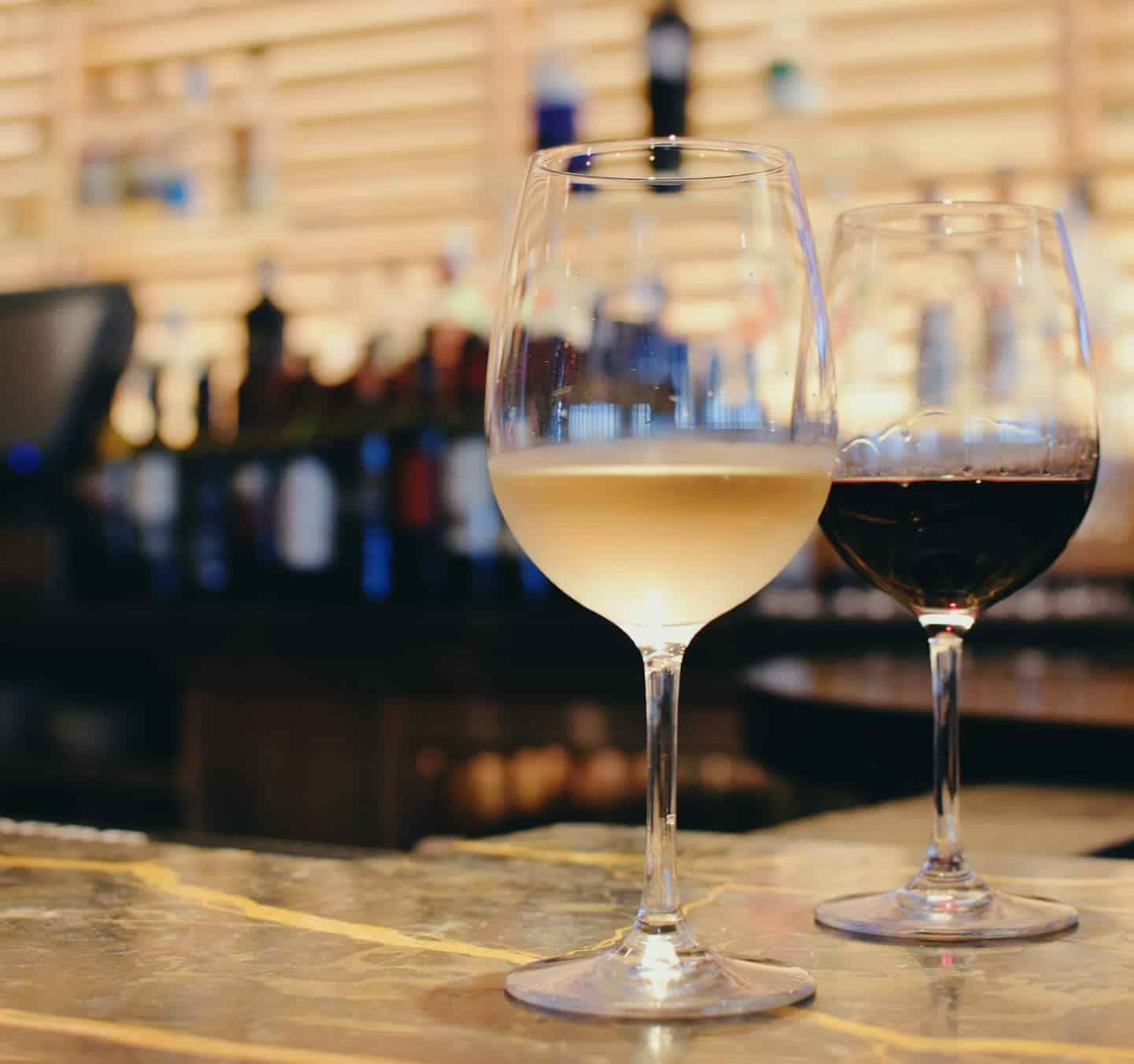 Due calici di vino bianco e rosso su un bancone di marmo.